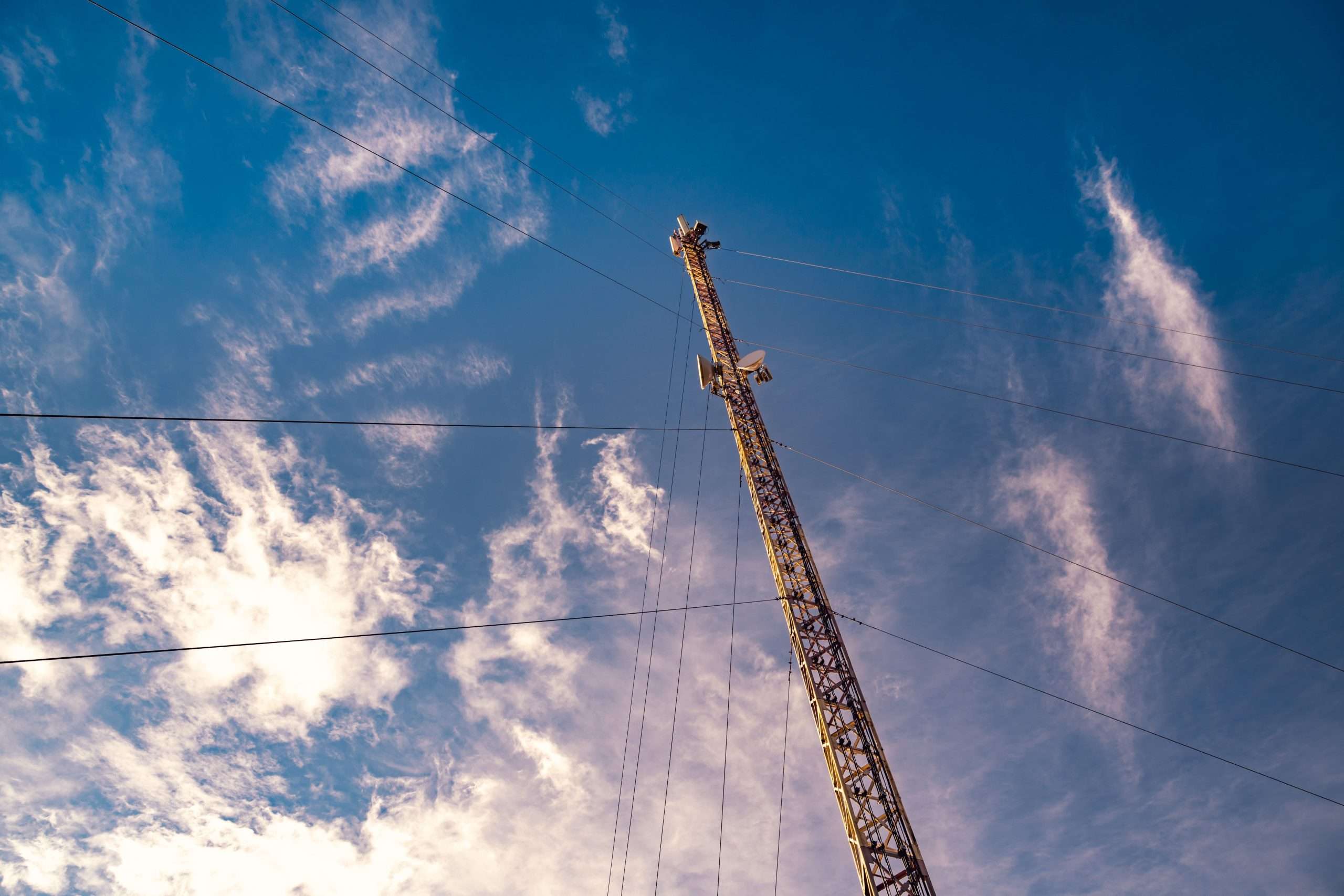 Telecommunication tower against the backdrop of an awesomely beautiful sky with blurry snow-white clouds